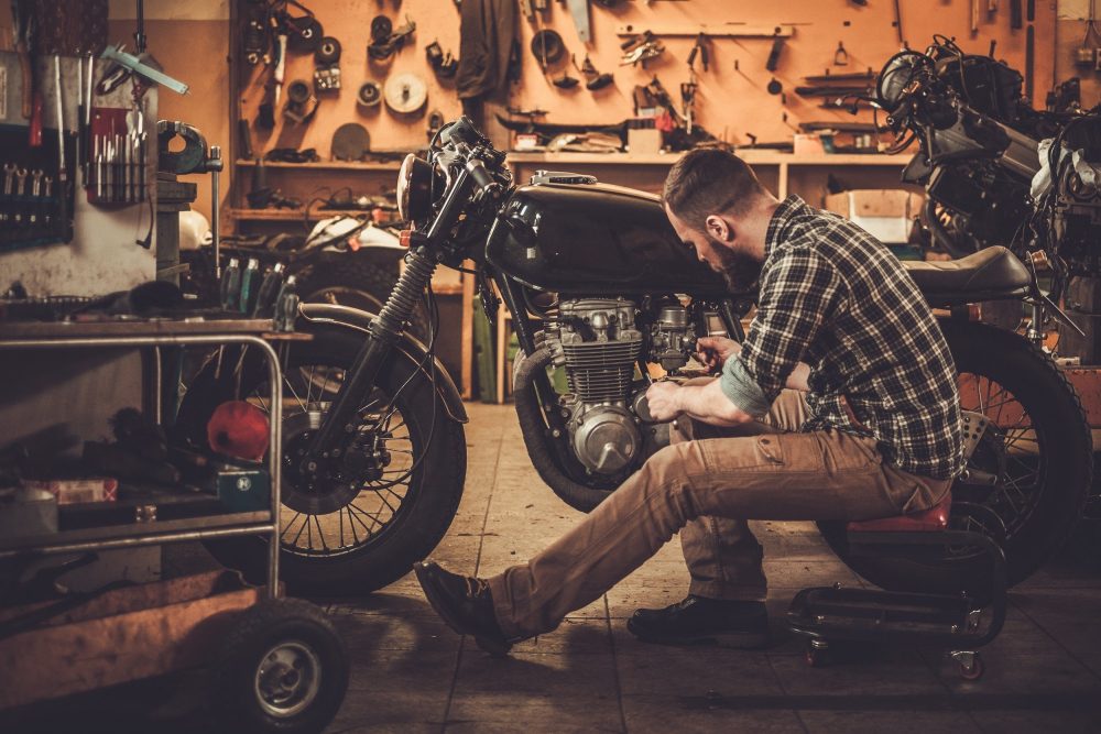 Mechanic building vintage style cafe-racer motorcycle in custom garage